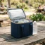 asset_2210dd598cb7c3f0 RTIC Ice Lunch Bag open on a sunny outdoor picnic table packed with drink cans and a chilled water bottle.