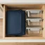 asset_a174f4ff5a1a80ca RTIC Ice Lunch Bag folded flat and slid into a shallow kitchen drawer beside plain stacked containers.
