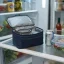 asset_a6738de78fbfc19c RTIC Ice Lunch Bag open on a refrigerator shelf next to a chilled drink can and a covered food container.