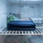 asset_aef56c364bd7a9a6 RTIC Ice Lunch Bag lying empty and folded flat on a home freezer shelf with light frost nearby.